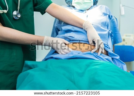 Woman doctor using a hand to hold the belly fat Of obese woman patients, who received treatment for abdominal fat reduction surgery from obesity, to people health care and surgery concept.