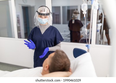 Woman Doctor Wearing PPE Suit And Surgical Mask And Checking Infected Patient In Quarantine Room Covid-19