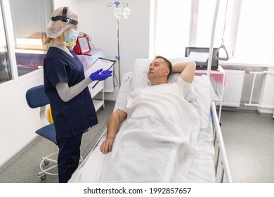 Woman Doctor Wearing PPE Suit And Surgical Mask And Checking Infected Patient In Quarantine Room Covid-19