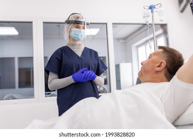 Woman Doctor Wearing PPE Suit And Surgical Mask And Checking Infected Patient In Quarantine Room Covid-19