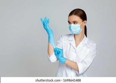 woman doctor in white uniform wearing mask and rubber gloves on gray background. copy space