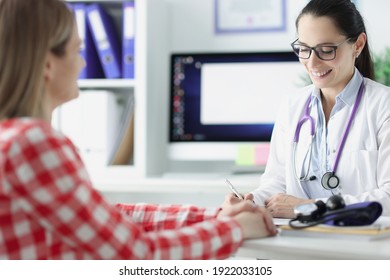 Woman Doctor Writing In Medical History And Talking With Patient. Outpatient Care Concept