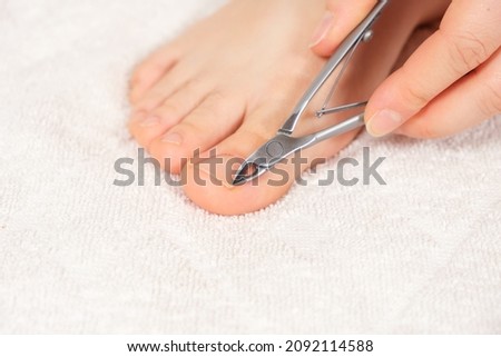 A woman does a pedicure in a beauty salon, removes the cuticle from the big toe with pliers.
