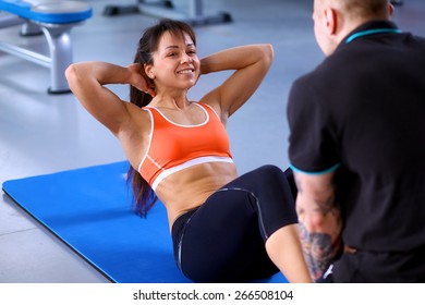 Woman Does Situps With Coach In Training Gym