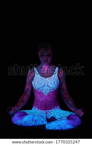 Woman does yoga, hand movement, body warm-up. Art girl cosmos in ultraviolet light. Entire body is covered with colored droplets. Astral yoga. Noise, out of focus
