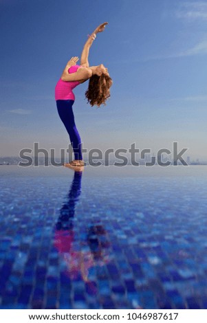 Woman does yoga on the edge of a pool overlooking Los Angeles