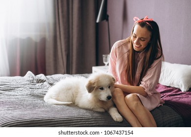 Woman with dog in bed - Shutterstock ID 1067437154