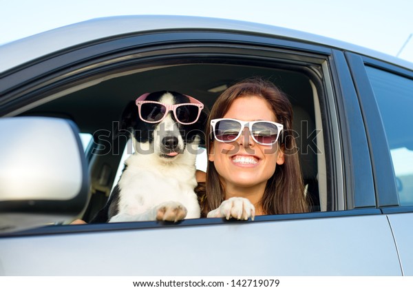 Woman and dog in\
car on summer travel. Funny dog with sunglasses traveling. Vacation\
with pet concept.