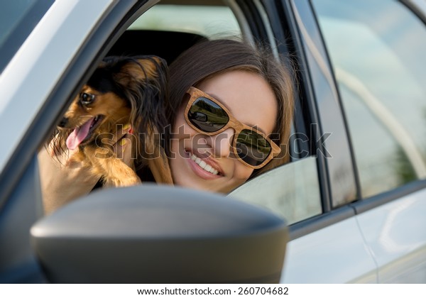 Woman and dog in car on summer travel. Funny\
dog traveling. Vacation with pet\
concept.