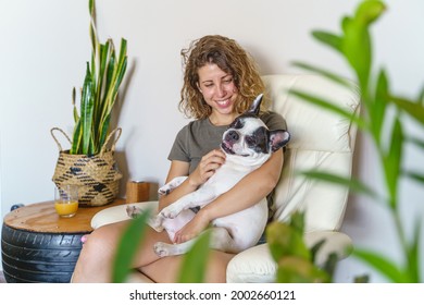 Woman Dog Lover With Bulldog At Home. Horizontal View Of Woman Tickling Dog Isolated With Plants.