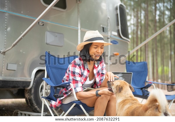Woman and  dog near the camping. caravan\
car vacation. family vacation travel, holiday trip in\
motorhome.camping on a hill while sitting on the ground by the car\
and having relaxing\
conversation.