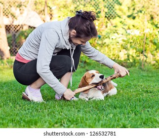 woman and dog plays with a stick on a lawn