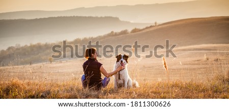 woman with dog relaxing in autumn landscape