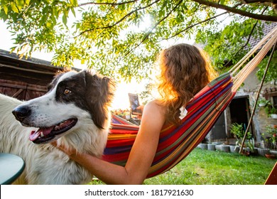 Woman With Dog Relaxing In Hammock In Back Yard