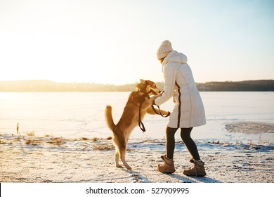 Woman With Dog Walking Down The Village Street In The Snow