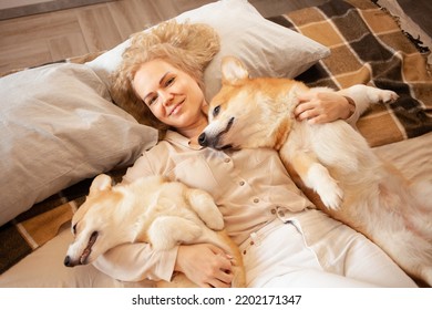 Woman And Dogs Lie On Bed, Family, Smiling. Relax, Spend Time Together, Enjoy And Have Fun. Lifestyle, Everyday Life. Look At Camera