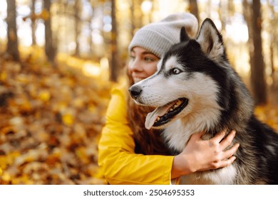 Woman with dogs in the park in autumn. Outdoor activities with a pet, walk, play.  Husky dog. Friendship, pet and human. - Powered by Shutterstock