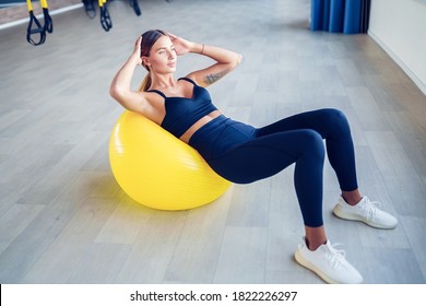 Una mujer haciendo pilates de crunches abdominales ejercita sobre el ejercicio de fitness ball en el gimnasio. Ejercicios para los abs. Balón suizo. Esfuerzo, dedicación y concepto de motivación.