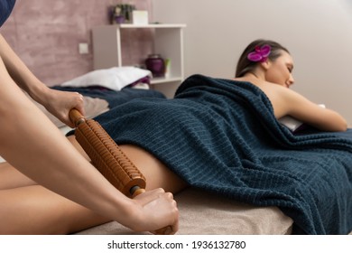 Woman doing anti cellulite massage with wooden rolling pin