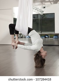 Woman Doing Anti Gravity Yoga Exercise In Fitness Center.