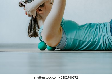 Woman doing back muscles myofascial release with two therapy massage balls. Concept: self care practices at home, physical health, fascia hydration, back muscle rejuvenation