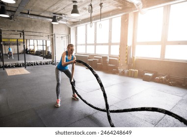 Woman doing battle rope training. Routine workout for physical and mental health. - Powered by Shutterstock