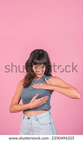 Woman doing a Breast Self-Exam checking up breast changes over pink background. Copy space