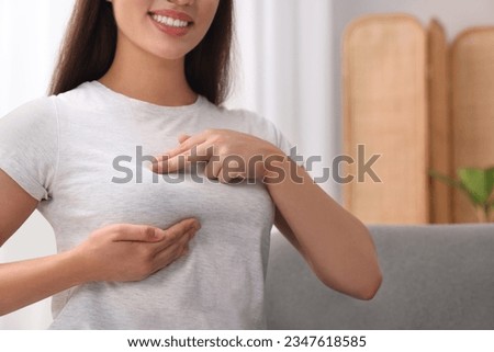 Woman doing breast self-examination at home, closeup. Space for text
