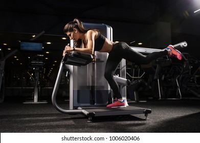 Woman doing buttocks exercises on gym equipment. Copy space. Sport, fitness, strength training and people concept.