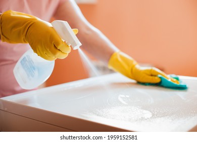 woman doing chores in bathroom at home, cleaning surfaces sink and faucet with spray detergent suds sponge.