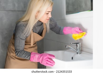 Woman Doing Chores In Bathroom At Home, Cleaning Sink And Faucet With Spray Detergent.