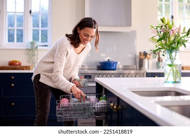 Woman Doing Chores Loading Dishwasher In Kitchen At Home - Powered by Shutterstock