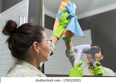 Woman doing cleaning in bathroom using vacuum cleaner, without use of household chemicals. Close-up of gloved hands with steam in the mirror, eco-friendly cleaning - Powered by Shutterstock