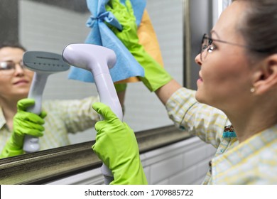 Woman doing cleaning in bathroom using vacuum cleaner, without use of household chemicals. Close-up of gloved hands with steam in the mirror, eco-friendly cleaning - Powered by Shutterstock