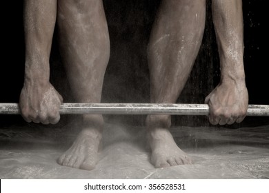 A Woman Doing A Dead Lift Close Up With Powder On Her Legs And Arms.
