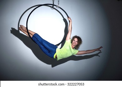 Woman doing entertainment exercise with aerial hoop midair in spotlight - Powered by Shutterstock