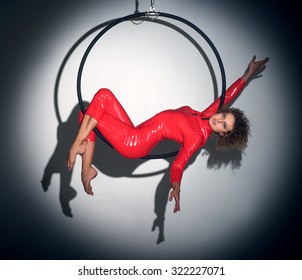 Woman doing entertainment exercise with aerial hoop midair in spotlight - Powered by Shutterstock