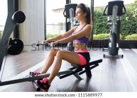 Woman doing exercise for her back in the gym. Seated cable row.