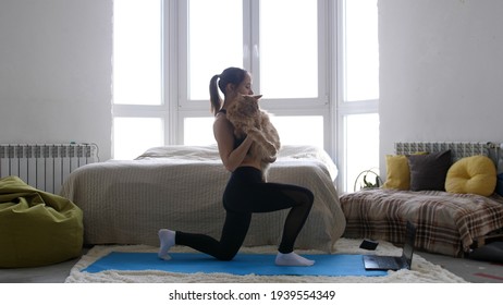 Woman Doing Exercise Workout Online Personal Trainer Watching An Online Course On The Computer And Maine Coon Cat Is Sitting Side By Side In Room. During Quarantine.