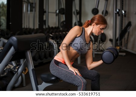 Woman doing exercises with dumbbells in the gym