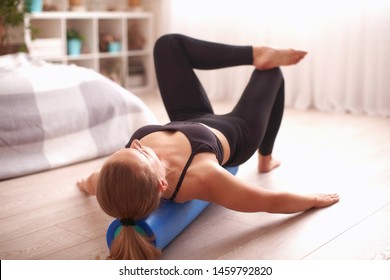 woman doing exercises, lying back on the roller, balancing. blonde sports clothes, home exercise Strengthens your muscles.the girl is working Treherne zone.girl gymnastics with roller