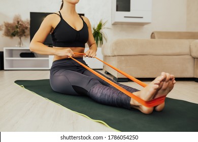 Woman Doing Exercises With Resistance Bands At Home. Cropped Shot Of A Young Woman Exercising With An Elastic Band On The Floor. Workout In Home And Quarantine Concept.