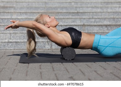 Woman Doing Fascia Exercise With Foam Roller On Back