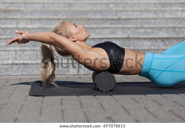 woman\
doing fascia exercise with foam roller on\
back