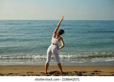 Woman Doing Fitness Exercise Outdoor Against Sea Background. Health, Retreat And Meditation Concept.