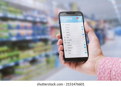 Woman doing grocery shopping at the supermarket, she is checking her shopping list on the smartphone