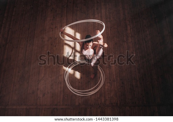 woman doing gymnastics exercises with hoop in\
gymnasium. Top view