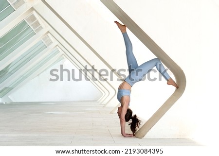 Woman doing a handstand against a concrete arch