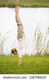 Woman Doing A Handstand By The Waterside