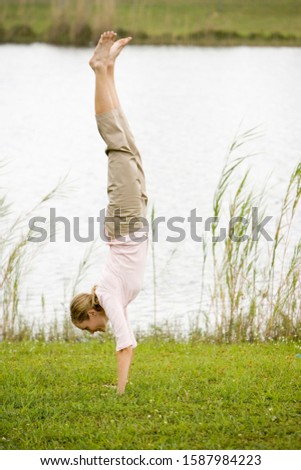 woman doing a handstand by the waterside